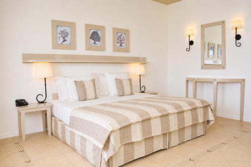 a white bedroom with a large bed with two lamps at Hotel Morabeza in Santa Maria