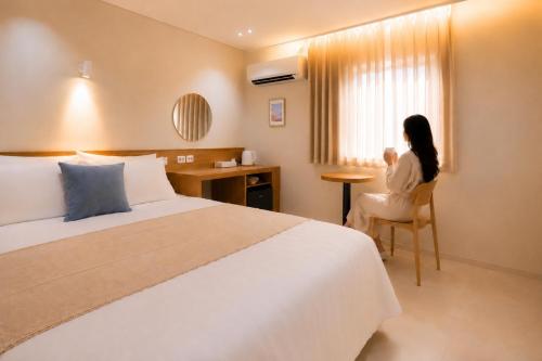 a woman sitting in a chair in a hotel room at 부산 수영 블루닷 호텔 in Busan