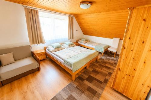 a bedroom with two beds and a couch and a window at Chata u pltníka Paľka in Podbiel