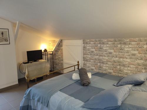a bedroom with a bed with a brick wall at Gîte du grand braquet in Puget-Théniers