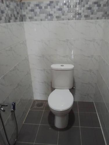 a bathroom with a white toilet and a shower at Melor Guest house in Kampong Telok Dalam