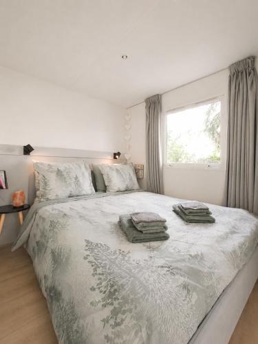 a bedroom with a large bed with two towels on it at The Red Shutter Cottage in Hattemerbroek