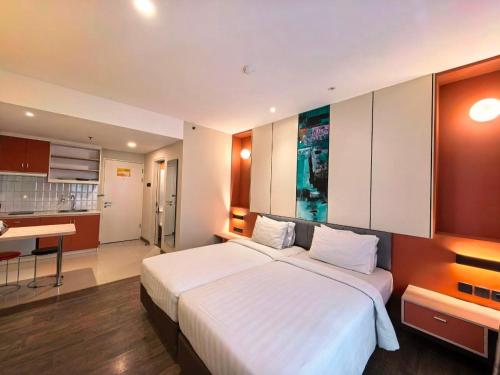 a bedroom with a large white bed and a kitchen at Marra Hotel in Yogyakarta