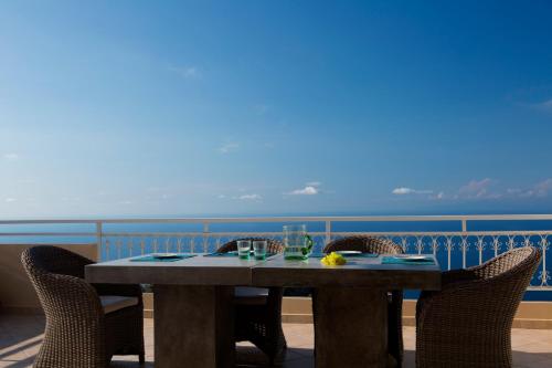 a table on a balcony with a view of the ocean at Amalia Apartments in Exanthia