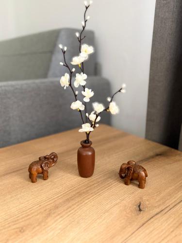 a table with a vase with flowers and two toy elephants at Pine Forest Apartments in Pamporovo