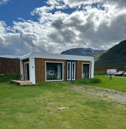 a small house in a field with mountains in the background at Løkvollstranda camping As in Samuelsberg