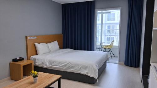 a bedroom with a bed and a table and a window at Firstcity Hotel YEOSU in Yeosu