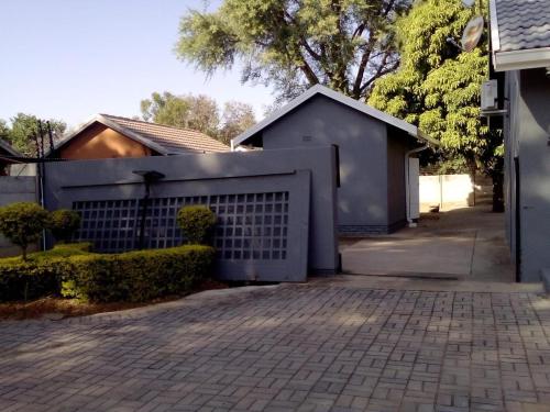 a house with a white fence and a driveway at Vhulinganela Guest House in Ellisras