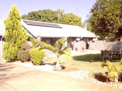 a house with palm trees in front of it at Vhulinganela Guest House in Ellisras