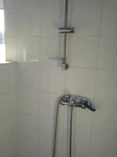 a shower in a white tiled bathroom with a sink at Casinhas do Ribeiro in Póvoa de Lanhoso