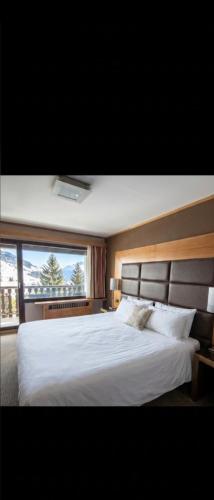 a bedroom with a large white bed with a window at Le Cocon des 2 Alpes, Spa, Jacuzzi, Piscine Chauffee in Les Deux Alpes