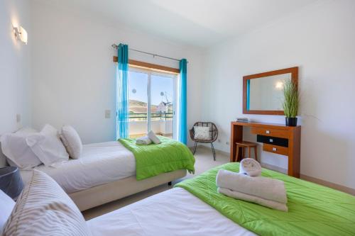 a bedroom with two beds and a desk and a window at Casa Iguana in Budens