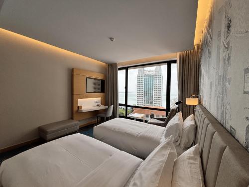 a hotel room with two beds and a large window at OZO George Town Penang in George Town
