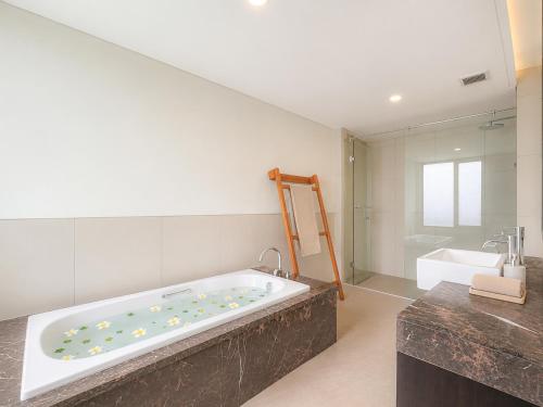a large bathroom with a large tub and a sink at Tridi Beach Villa by Nagisa Bali in Tanah Lot