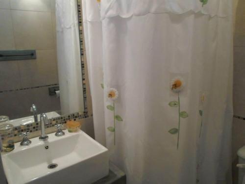 a bathroom with a sink and a shower curtain with flowers on it at La Ignacia Bed and Breakfast in Pilar