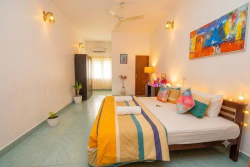 a bedroom with a large bed with colorful pillows at VILLA MANTRAA in Varkala
