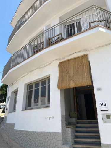 a white house with a balcony and stairs at Hostal Boutique Es Grop in Port de la Selva