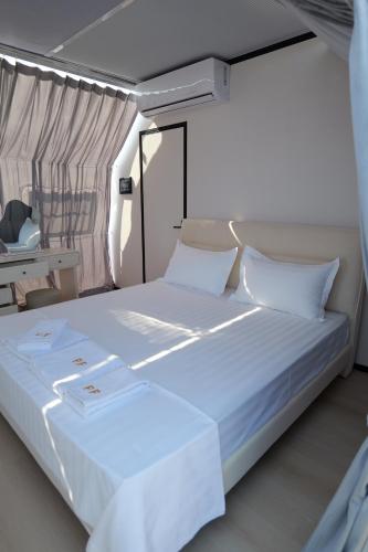 a bedroom with a large white bed with white pillows at Piccolo Paradiso - Glamping Resort in Shëngjin