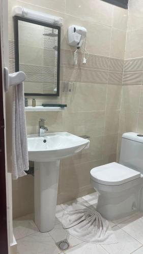 a bathroom with a sink and a toilet and a mirror at Hôtel La Miséricorde in Douala