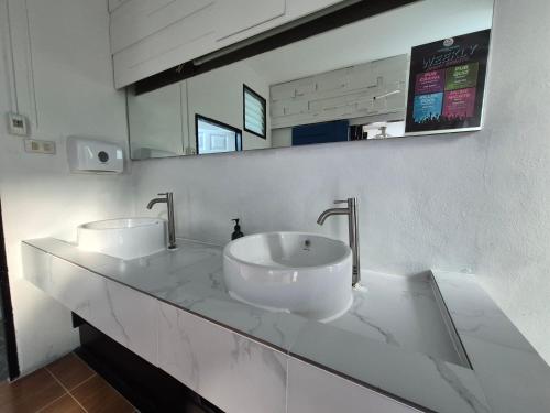 a white bathroom with two sinks and a mirror at The Hangout Hostel Ao Nang in Ao Nang Beach