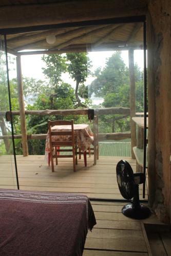 a bedroom with a table and a chair on a porch at Canto de Paz Trindade Hospedagem in Trindade