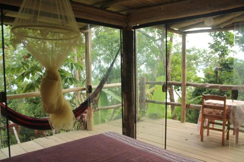 a hammock on a screened in porch with a table at Canto de Paz Trindade Hospedagem in Trindade
