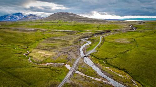 an aerial view of a road in a field with a river at Laugarfell Accommodation & Hot Springs in Laugarfell