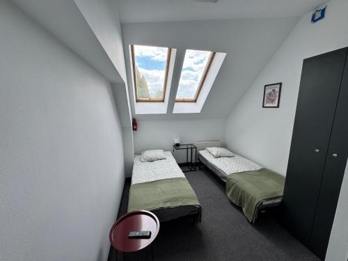 two beds in a small room with two windows at Willa Konstancja in Aleksandrów Łódzki