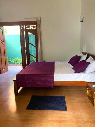 a bedroom with a large bed with purple pillows at Villa Nadika in Beruwala