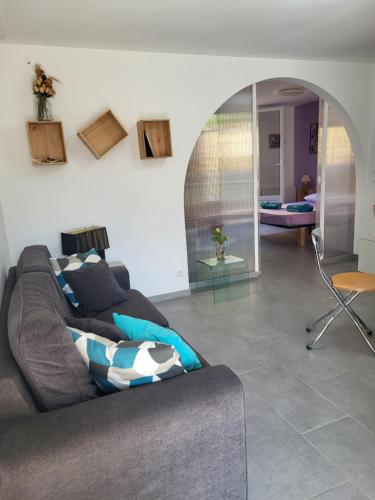 a living room with a gray couch and a chair at Paisible T2 climatisé avec jardinet in Béziers