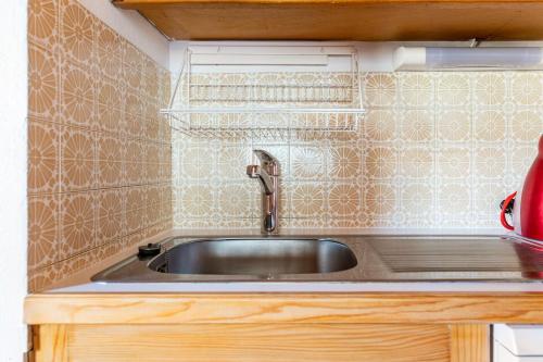a kitchen with a sink and a tiled wall at Large Méribel Three Valleys in Les Allues