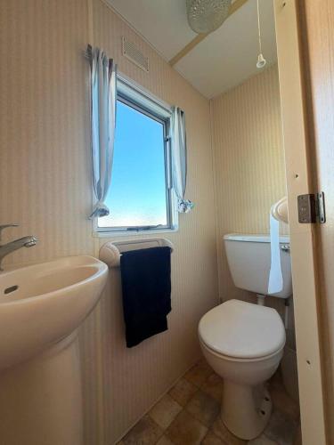 a bathroom with a toilet and a sink and a window at Skegness Seaside Escape in Ingoldmells