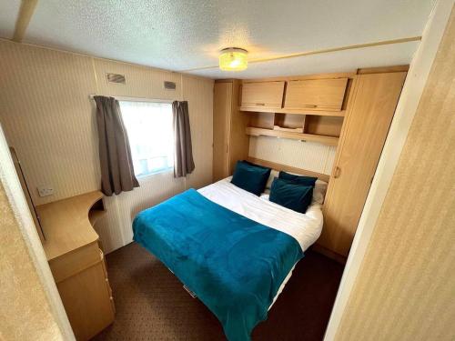 a small bedroom with a bed with blue pillows at Skegness Seaside Escape in Ingoldmells