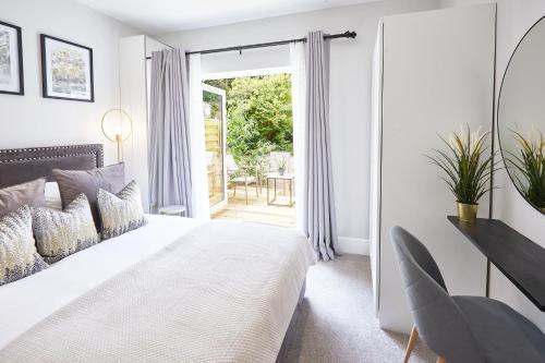 a white bedroom with a bed and a sliding glass door at The Madison Garden in Whitby