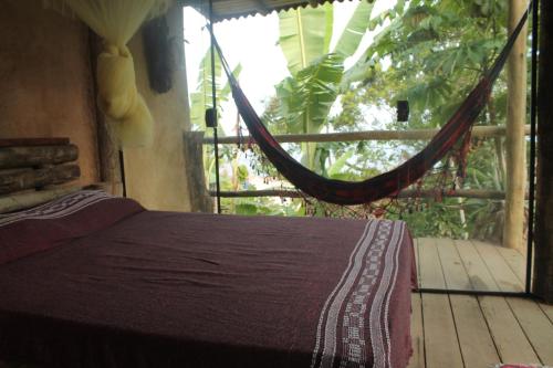 a bed with a hammock in a room with a porch at Canto de Paz Trindade Hospedagem in Trindade