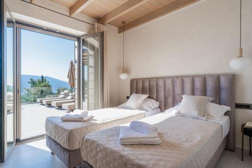 two beds in a room with a large window at Villa Thalassa by Villa Select in Fiskardo