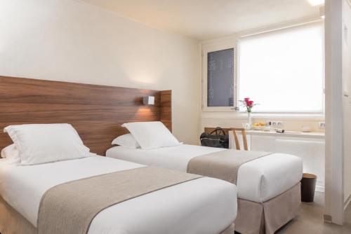 a hotel room with two beds and a window at Terre de Provence Hôtel & Spa in Le Pontet