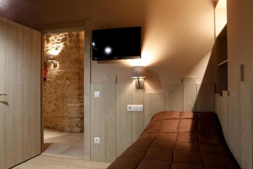 a bedroom with a bed and a flat screen tv at Cal Miqueló 1778 in Puig-Gros