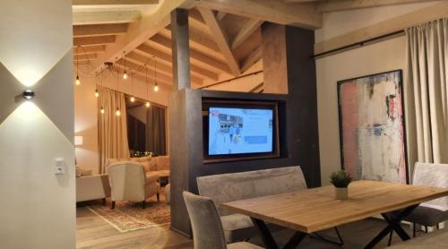 a dining room with a table and a television on a wall at B living Apartments in Neukirchen am Großvenediger