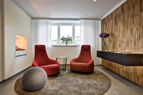 two red chairs and a table in a room at Hotel Gemma - Adults only in Hirschegg