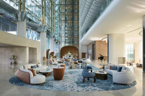 a lobby with couches and tables and a piano at The Meydan Hotel Dubai in Dubai