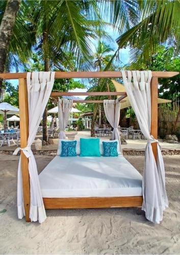 a canopy bed on a beach with palm trees at Soroi Blue - Diani Beach in Diani Beach