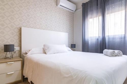 a bedroom with a large white bed with a window at Beach Palo Malaga in Málaga