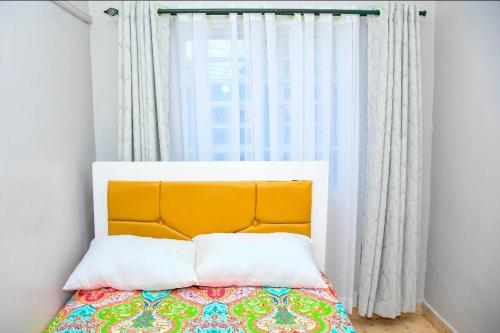 a bed with an orange headboard in a room with a window at Comfort Inn Nyeri in Nyeri