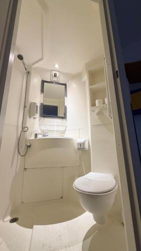 a small white bathroom with a toilet and a mirror at hôtel du grand sud in Ramonville-Saint-Agne