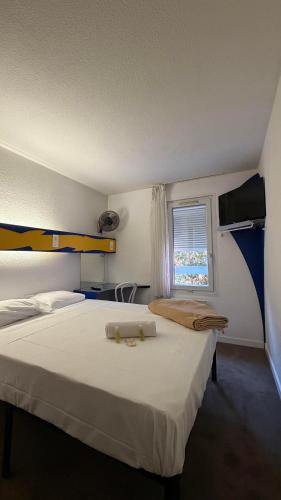 a bedroom with a large white bed and a window at hôtel du grand sud in Ramonville-Saint-Agne