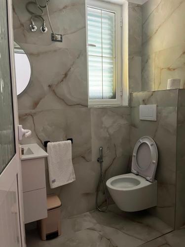 a bathroom with a toilet and a sink and a window at Kapo Residence in Vlorë