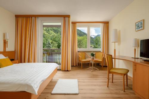 a hotel room with a bed and a table and chairs at Hotel PALACE in Bad Hofgastein