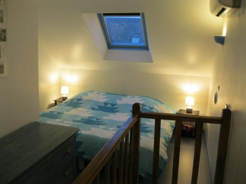 ein Schlafzimmer mit einem Bett mit blauer Decke und einem Fenster in der Unterkunft Le Clos des Alouettes in Amboise