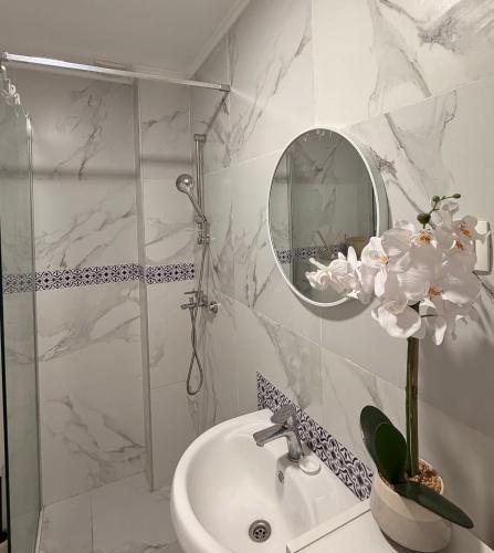 a bathroom with a sink and a shower with a mirror at Tiffany apartment - Podgorica in Podgorica
